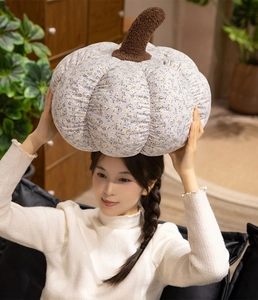 Detail of floral pumpkin plush pillow showing soft cotton fabric and brown stem texture
