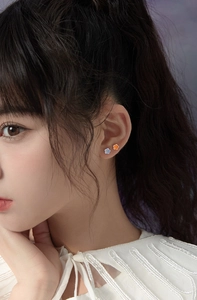 Close-up of asymmetric flower earrings in blue and orange on a model