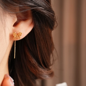 Close-up of a gold butterfly threader earring worn, showing the long tassel chain detail