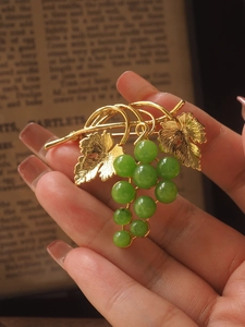 Detail of a vintage-style grape brooch with green beads and gold metallic leaves