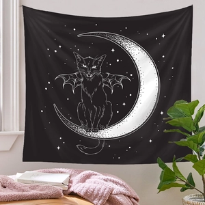 Detail of bohemian black cat tapestry with bat wings and crescent moon on a white wall