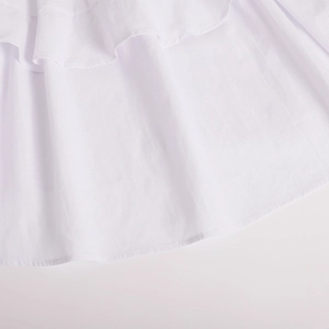 Detailed close-up of the white tiered ruffle layers and woven fabric texture