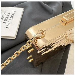 Detail of gold metallic hard shell evening clutch with pleated texture and chain strap