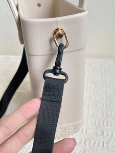 Detail of beige EVA tote bag featuring black nylon strap with golden metal buckle