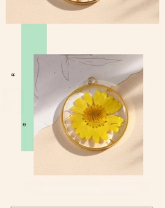 Close-up of handmade resin pendant with yellow dried flower in a gold copper ring frame