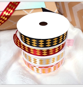 Detail of stacked gold rhombus pattern ribbons in black, red, white and pink colors