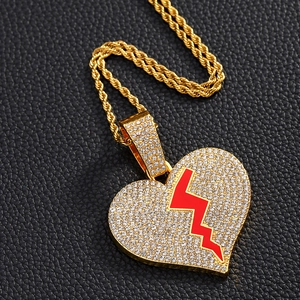 Détail d'un pendentif cœur brisé doré avec strass et émail rouge sur chaîne épaisse