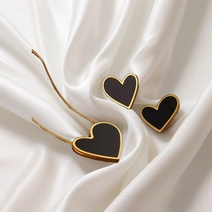 18K gold necklace and earrings set featuring black heart pendants on white silk