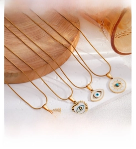 Detail of four gold Evil Eye necklaces with blue enamel charms on a wooden tray