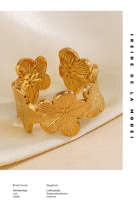 Close-up of golden floral open ring with matte textured petals on white silk