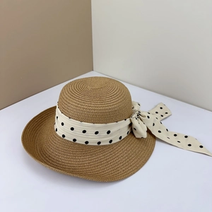 Detailed close-up of woven straw hat featuring wide brim and polka dot ribbon bow