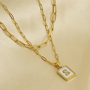 Detail of 18K gold-plated paperclip chain necklace with a square letter S pendant on silk