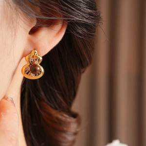 Close-up of vintage gourd earrings featuring brown beads and crystals on a model