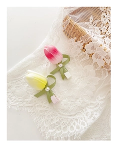 Detail of pink and yellow tulip hair clips with silk ribbons and pearls on lace fabric