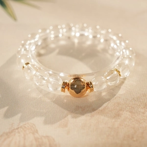 Macro shot of clear quartz crystal bracelet with a gold clover charm and spiral spacers