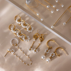 Détail d'un ensemble de boucles d'oreilles en acier doré 18K et perles chics