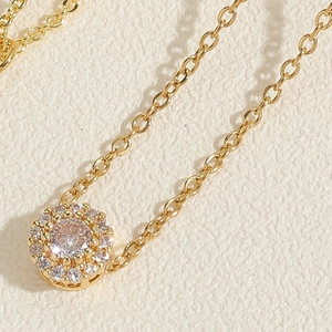 Macro detail of golden sunflower necklace featuring a sparkling zircon pendant