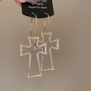 Detailed close-up of large gold hollow cross hoop earrings with 925 silver hallmarks