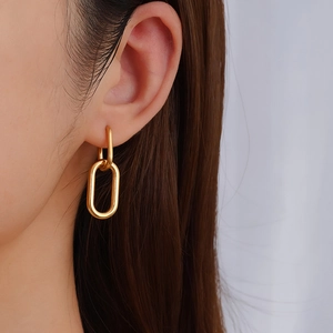 Minimalist gold U-shaped oval earrings with interlocking rings on a female model