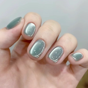 Close-up of short square-oval grey-green cat-eye press-on nails with magnetic shimmer