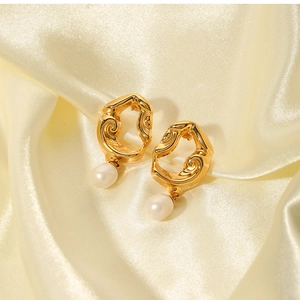 Detail of 18K gold-plated lava earrings with freshwater pearl charms on beige silk fabric