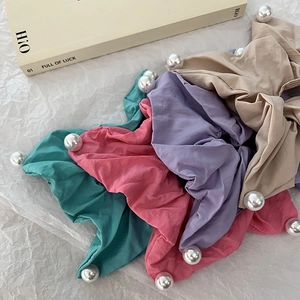 Chic fabric scrunchies with pearls in pastel colors displayed on white paper
