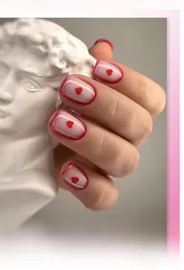 Detail of short square press-on nails with red heart pattern and French red border tips