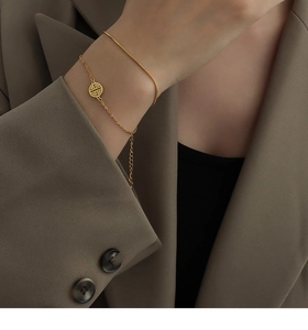 Detail of a 18k gold-plated double-layer snake chain bracelet with Chinese charm