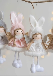 Close-up of plush angel doll ornaments with rabbit ears hanging on wooden branches