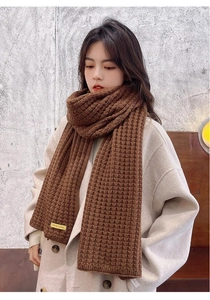 Detail of a brown thick knitted scarf with a 'handmade' label for winter warmth
