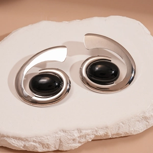Détail macro de boucles d'oreilles spirales en argent avec pierre d'onyx noire