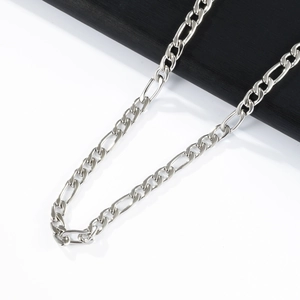 Macro shot of polished silver Figaro chain necklace showing intricate metal link details