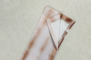 Close-up of double-stitched cuff on a brown tie-dye V-neck dress showing sewing detail
