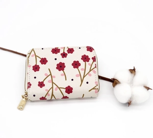 Floral accordion card holder with gold zipper detail and white cotton decor