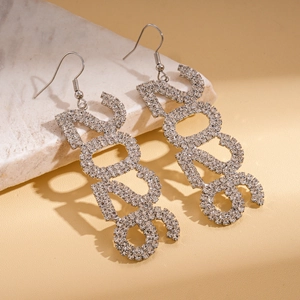 Macro shot of silver 2023 number earrings with sparkling rhinestones on marble stone