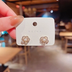 Detalle de pendientes de flores brillantes con perlas y cristales sobre una tarjeta