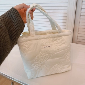 Detail of white quilted tote bag featuring 3D floral texture and simple wish tag