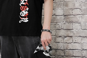 Gothic style silver titanium steel tiger head bracelet on male wrist against a brick wall