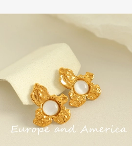 Detail of vintage gold flower earrings with white gemstones and lava metal texture