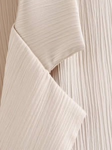 Gros plan sur la texture du tissu plissé beige du blazer à double boutonnage