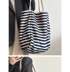 Detailed shot of large striped canvas tote bag with thick rope handles on shoulder