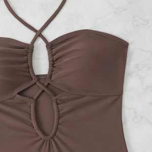 Détail d'un maillot de bain licou marron foncé avec découpe circulaire et tissu plissé