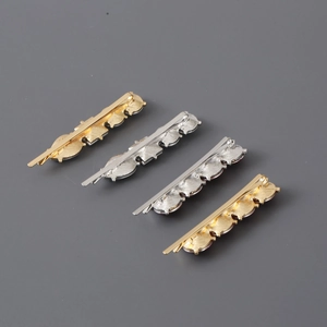 Detailed view of four wavy metal hair clips in textured gold and silver finishes