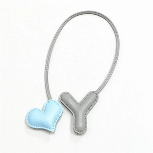 Dettaglio di un ciondolo per borsa in pelle fatto a mano con cuore blu e lettera Y grigia