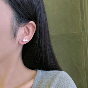 Close-up of a model wearing elegant silver bow earrings with sparkling clear zircons