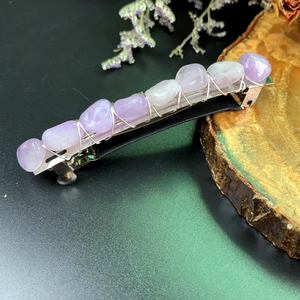 Detailed view of handmade purple crystal hair clip with silver wire wrapping on wood