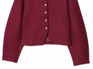 Dettaglio di un cappotto di lana bordeaux con bottoni metallici e trama del tessuto