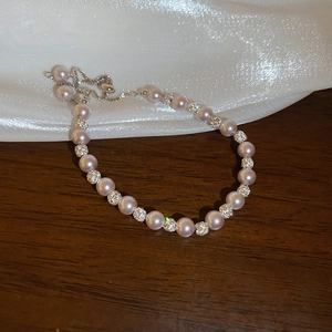 Gros plan d'un bracelet en perles rose-violet avec boules de strass et fermoir coulissant