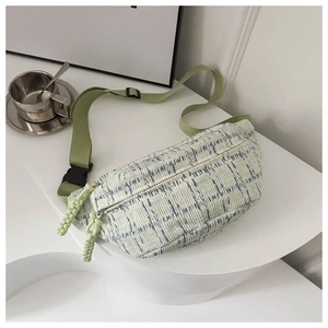 Detail of blue striped fabric waist bag with green zipper and adjustable strap