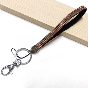Detailed view of rose gold rhinestone phone lanyard with silver metal clasp on wood